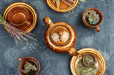 Çaydanlık ve şifalı bitkiler masada. Masadaki fincanda Heather bitkisel çayı. Düz yatıyordu.