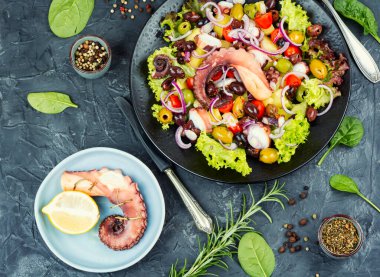 Otlu, patatesli ve zeytinli bir tabak ahtapot salatası. Üst görünüm.