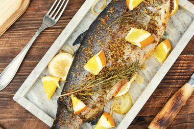 Baharatlı ve portakallı leziz kızarmış alabalık ahşap zemin üzerinde servis tahtasında. Kapat..