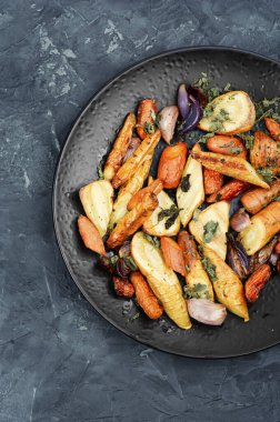 Besleyici tabakta kızarmış kök sebzeler sergileniyor. Vegan yemeği için ideal.