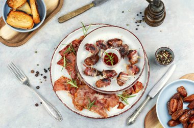 İştah açıcı aperatifler, pastırmaya sarılmış hurma tabakları. Üst görünüm.