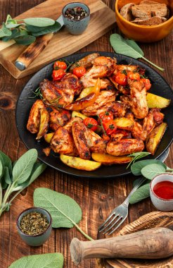 Fırında tavuk kanadı, patates ve adaçayı. Kırsal biçim.