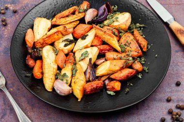 Besleyici tabakta kızarmış kök sebzeler sergileniyor. Sağlıklı sonbahar yemekleri.