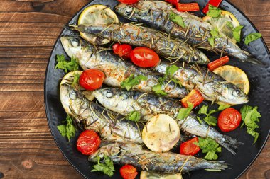 Çeri domatesli, biberiyeli ve limonlu sardalya ve sade ahşap masa. Kırsal biçim.