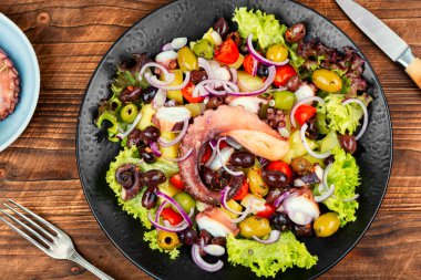 Ahtapot, patates, zeytin ve sebzeli ahşap bir masada iştah açıcı salata. Lezzetli aperatif. Kırsal biçim.