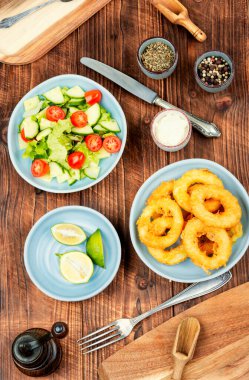 Ahşap arka planda soslu kalamar halkaları..