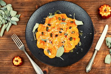 Köy ahşap masasında adaçayı soslu balkabaklı ravioli. Ravioli, tereyağlı ve adaçayı soslu. Üst görünüm.