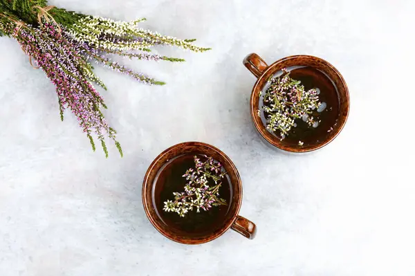 Kupada Heather bitkisel çayı ve masada orman otları. Metin için boşluk.