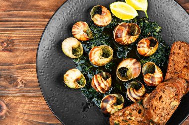 Salyangoz ya da tereyağlı salyangoz. Salyangozlar kırsal ahşap masa üzerinde hassaslaşır..