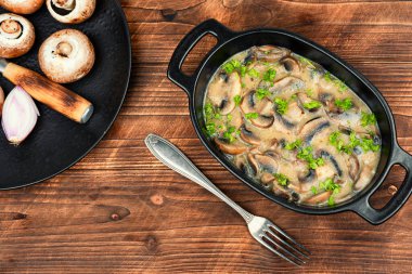 Kırsal ahşap masada kremalı sosta pişirilmiş mantarlar..