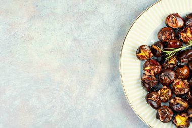 Kavrulmuş kestaneler, kavrulmuş kestaneler... Bazı kestaneler çatlamış, taze biberiye ile süslenmiş, sonbahar yapraklarıyla şekillendirilmiş. Boşluğu kopyala.