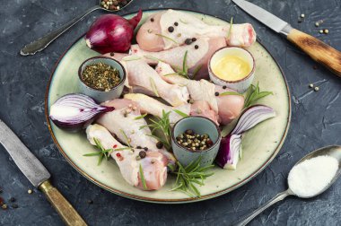 Baharatlı taze tavuk budu, salamura ve tabakta otlar..