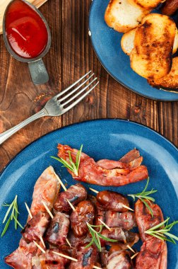 Lezzetli atıştırmalıklar, ahşap arka planda pastırmaya sarılmış hurmalar. Makro, pastırma şişleri ile tarihi kapat..