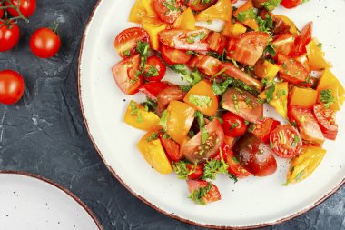 Seramik tabakta renkli domatesli taze çiğ salata.