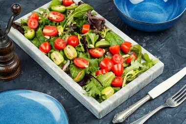 Yaz yeşillikleri ve domates salatası şık bir taş tepside. Sağlıklı vejetaryen gıda kavramı.