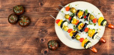 Barbecue vegetable skewers on from tomato, zucchini, pepper. Vegetarian food. Space for text. clipart