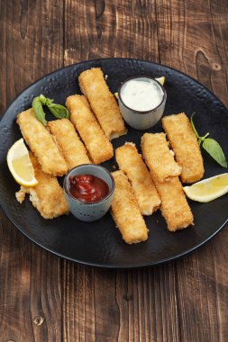 Limon ve sosla servis edilen kızarmış balık kroketleri. Kırsal ahşap masada balık külçeleri.