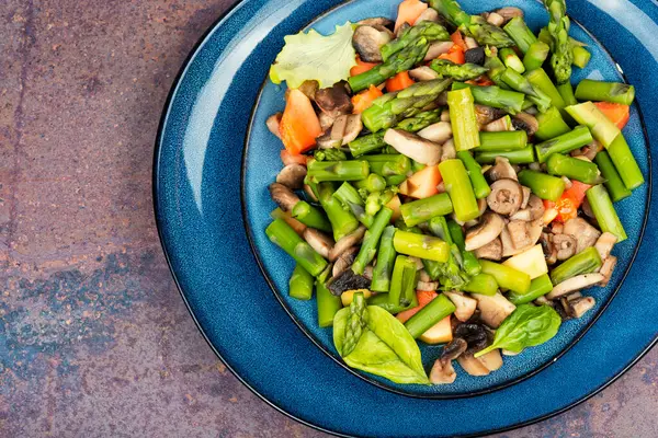 Yeşil kuşkonmaz salatası ve tabakta kızartılmış mantar. Boşluğu kopyala.