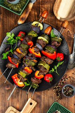 Şişte ızgara geyik şiş kebabı. Terbiye edilmiş et şişleri, rustik ahşap masada kızartılmış geyik eti.