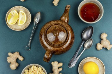 Ceramic teapot with fresh natural tea from fresh ginger root, honey and lemon, medicinal drink or tea. Top view. clipart