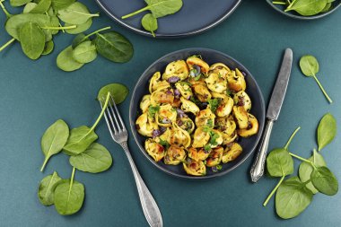 Taze yeşilliklerle süslenmiş mantı ya da ravioli tabağı. Üst görünüm.