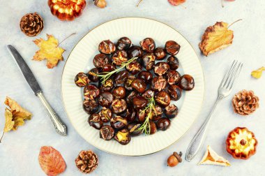 Kavrulmuş kestaneler, kavrulmuş kestaneler... Bazı kestaneler çatlamış, taze biberiye ile süslenmiş, sonbahar yapraklarıyla şekillendirilmiş. Üst görünüm.