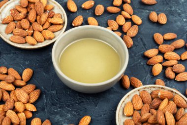 Kavrulmuş badem fıstığı. Tabakta doğal badem yağı ve masada fındık..