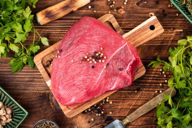 Baharatlı biftek eti ve ahşap kırsal arka planda taze otlar..