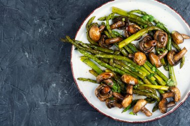 Kızarmış yeşil kuşkonmaz ve şampiyon mantarlardan oluşan Aromatik beslenme yemeği. Gurme mutfağı. Boşluğu kopyala.