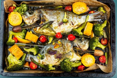 Fırında kızartılmış balık ve sebzeler. Baharatlı ve kızarmış sebzeli Dorado balığı..