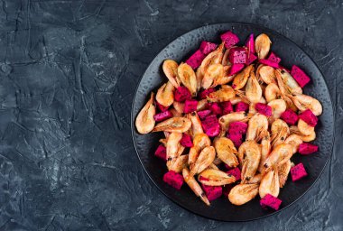 Meyve-sarımsak salamurasında taze kırmızı pitaya ya da tropikal ejderha meyvesi ile servis edilen lezzetli bir tabak karides. Boşluğu kopyala.