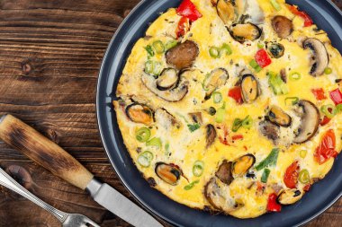 Tahta kırsal arka planda sebzelerle süslenmiş lezzetli midyeli omlet veya frittata. Protein iştah açıcı lezzetli besin.