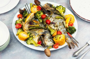 Kızarmış dorado balığı, haşlanmış brokoli, mısır ve kuşkonmaz. Deniz ürünleri şişleri..