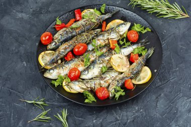 Limon, vişneli domates ve biberiyeyle süslenmiş ızgara sardalya tabağı. Yunanistan mutfağı.