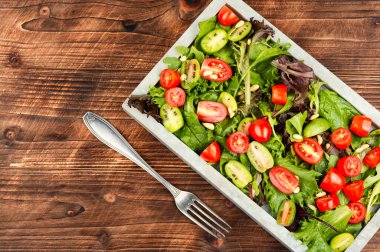 Ahşap arka planda zarif bir taş tepside aromatik otlarla nefis taze organik domates salatası. Boşluğu kopyala.