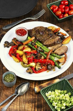 Güzel pişmiş ızgara ördek göğsü ahşap bir yüzey üzerinde beyaz bir tabakta servis edilir..