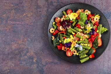 Kızarmış karides, yenilebilir çiçekler ve sebzeli taze deniz ürünleri salatası. Boşluğu kopyala.