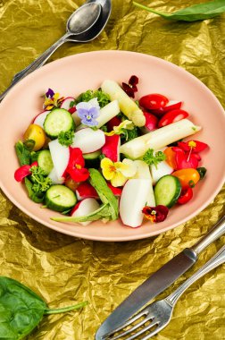 Yenilebilir çiçeklerle süslenmiş beyaz kuşkonmazlı sebze salatası. Vejetaryen mutfağı.