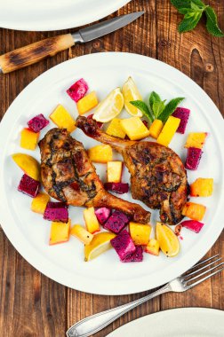 Kırsal ahşap masada meyve salamurasında pişirilmiş iki ördek bacağı. Yemek fotoğrafçılığı.