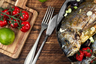 İki fırında Dorado balığı, bir tabak baharat ve kızarmış domates. Yemek fotoğrafçılığı.