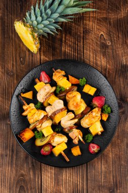 Ahşap arka planda taze ananaslı kızarmış tavuk kebabı.