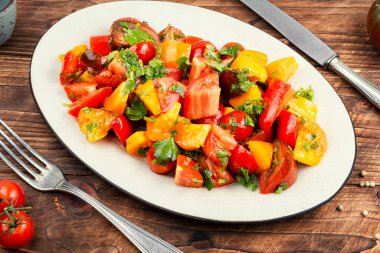 Seramik tabakta renkli domatesli taze çiğ salata.