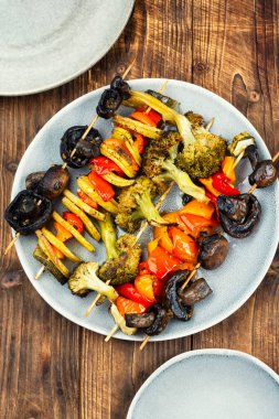 Kırsal ahşap masada vejetaryen ızgara şişleri. Kızarmış mantar, domates, dolma biber, brokoli ve kabak..