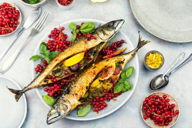 Bir tabak ızgara balık, limonlu kızarmış uskumru balığı, soğan ve kırmızı frenk üzümü. Genel Görünüm.