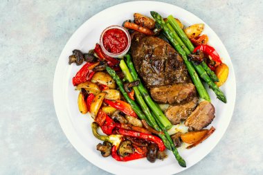 Fırında pişirilmiş ördek göğsü fırında sebzelerle süslenmiş beyaz bir tabakta servis edilir..