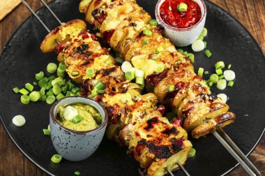 Masada servis edilen bir tabak et şişi ve bebek patatesi..