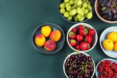 Masada taze lezzetli meyveler var. Sağlıklı yiyecekler. Üzüm, üzümler, çilek ve vişneli kayısı. Metin için boşluk.