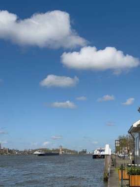 Hollanda, Hollanda 'da Dordrecht' ten yelken açan iç mavna nakliye gemisi Maas 'ın sakin nehir suyunda. Malları taşıyan konteyner gemisi.