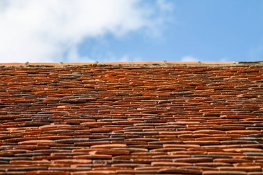 Eski bir İngiliz kulübesinin geleneksel çatısında turuncu döşemeler kendine özgü bir şekilde sıralanmıştır. Yıpranmış kiremitler karakteri ve sıcaklığı ekler, kulübenin zamansız cazibesini arttırır..