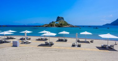 Yunanistan 'ın Kos adasındaki cennet adasının önündeki güzel Agios Stefanos Sahili' nin güverte sandalyesi ve şemsiyesi.